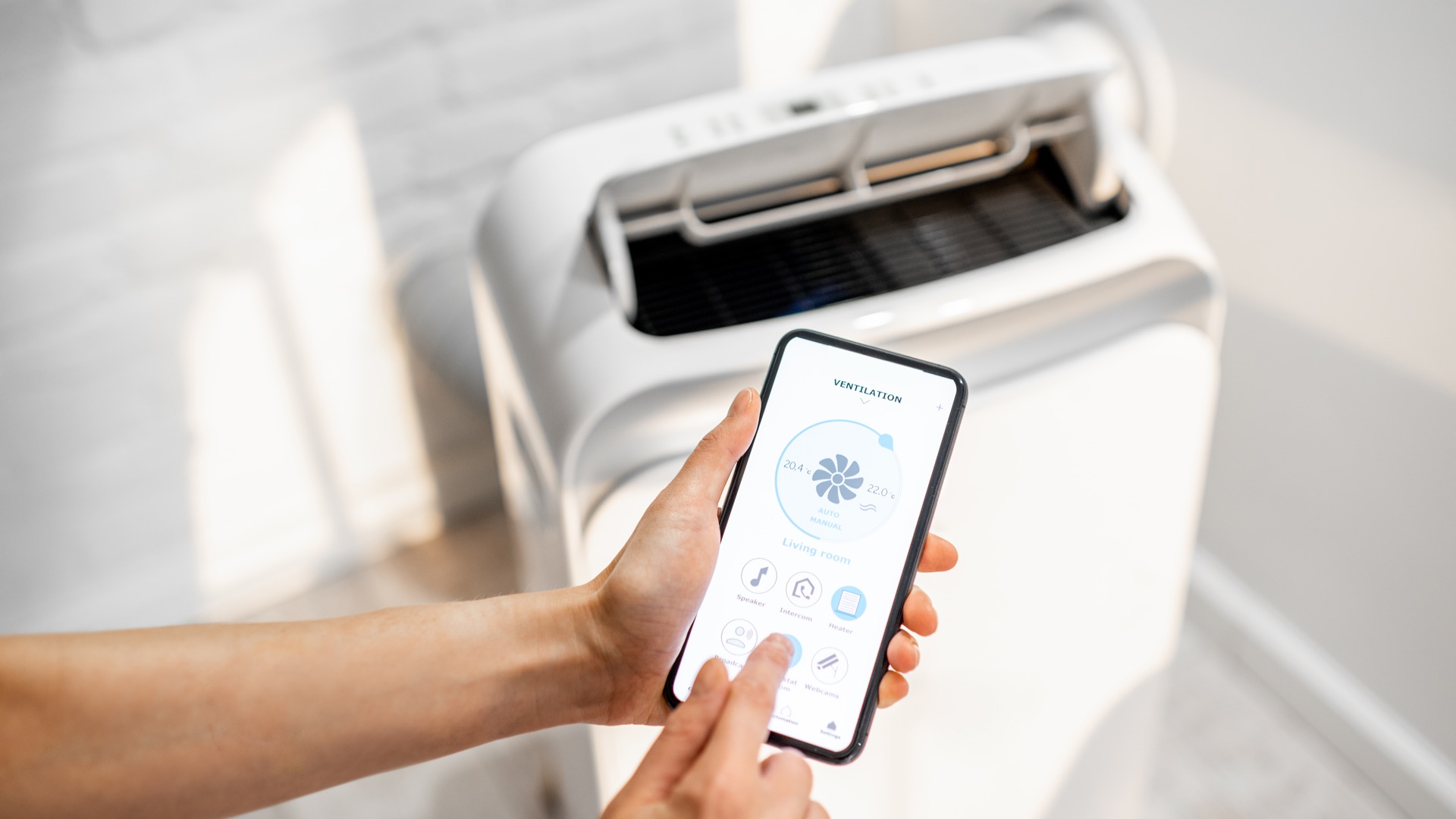 Personne pilotant un appareil de climatisation avec un smartphone