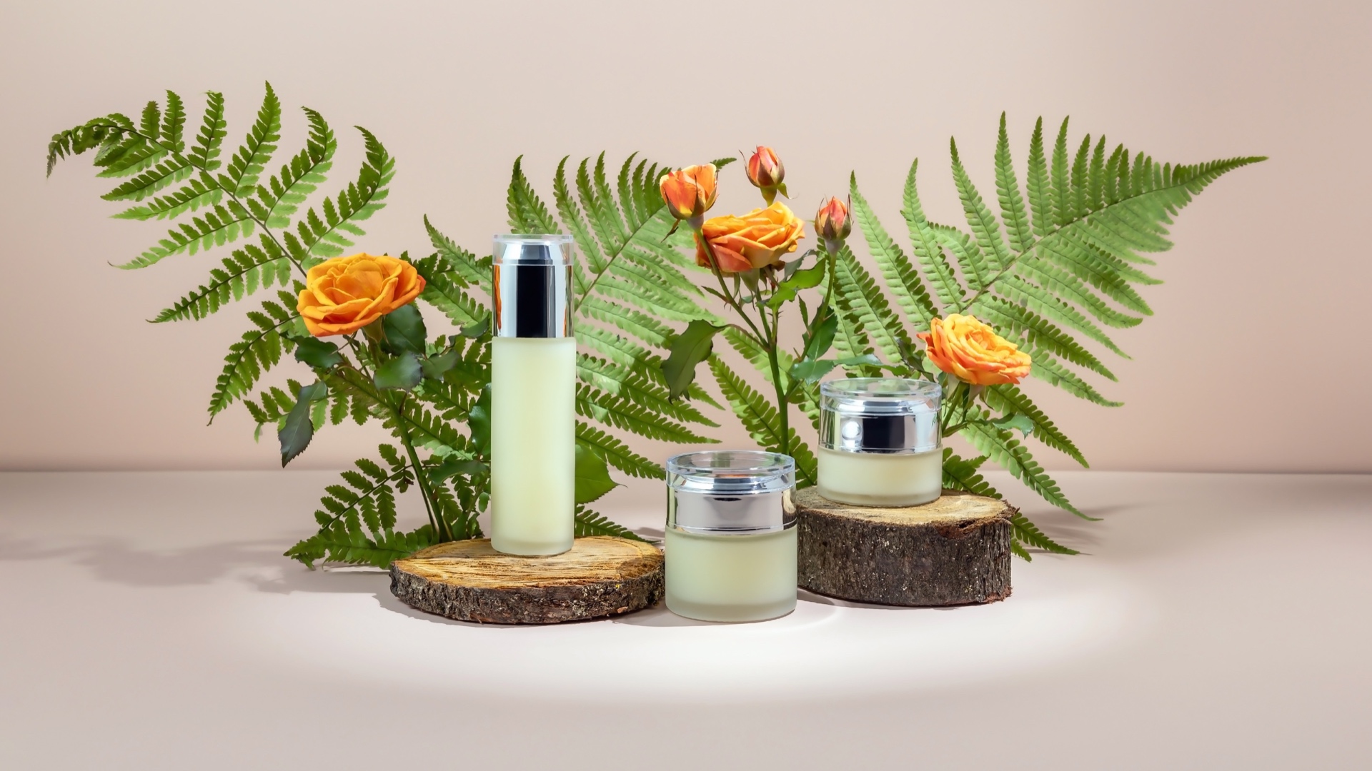 Flacons et pots de cosmétiques entourés de feuillage et de roses
